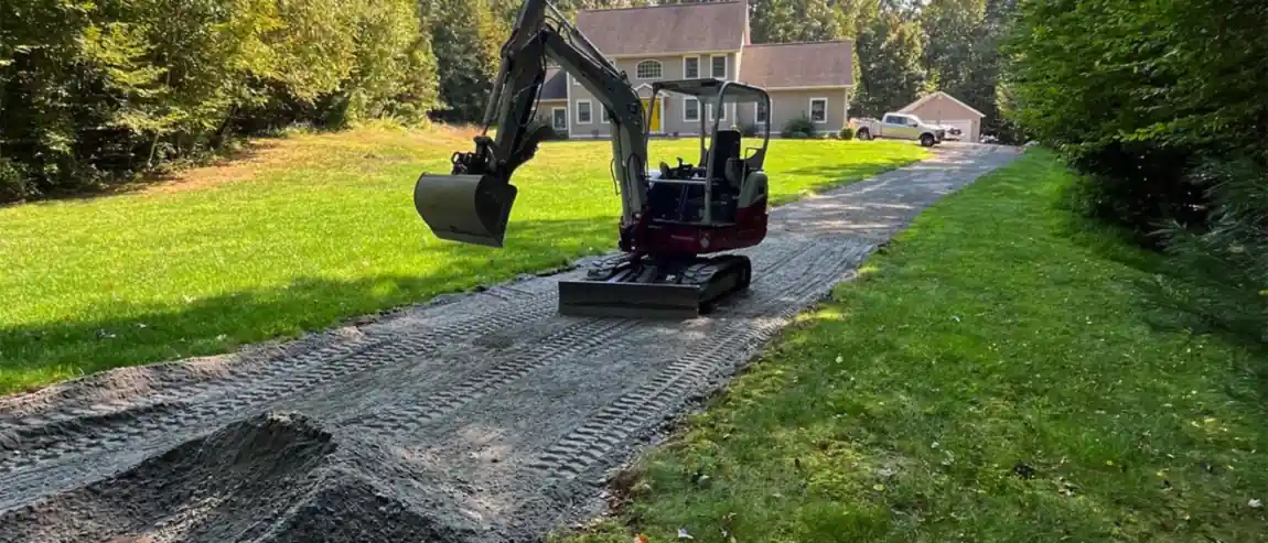 A newly built gravel driveway running up to a Connecticut home, with an excavator finishing the grade.