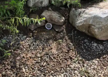 A stone drainage bed with a capped cleanout set in between boulders.
