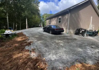 A driveway rebuilt beside a house, fresh soil worked along the new edge.