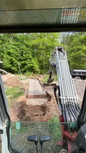 The view from inside the excavator cab, looking down the open trench.