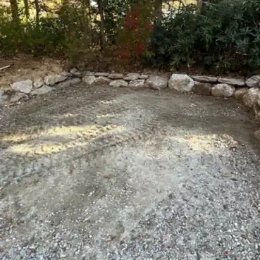 A gravel pad finished up against a stone wall.