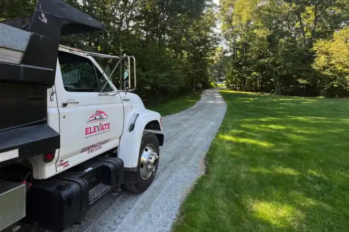 The Elevate Earth and Water Werks dump truck parked on a freshly graded gravel driveway.